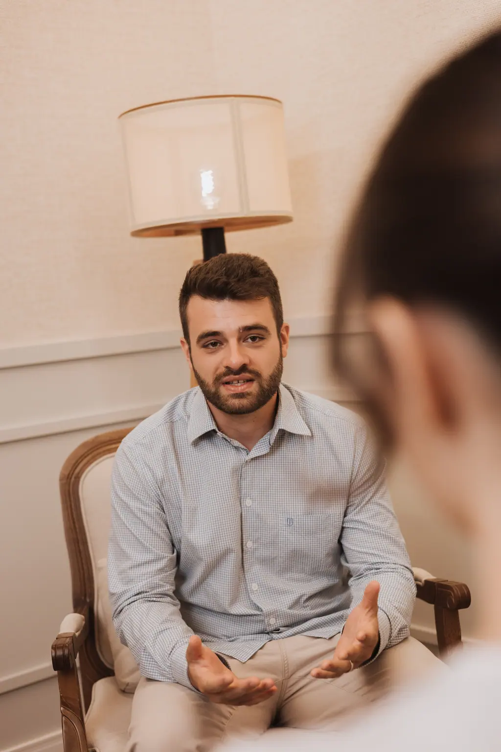 Dr. Lucas Vitório em atendimento no consultório, escutando uma paciente de costas