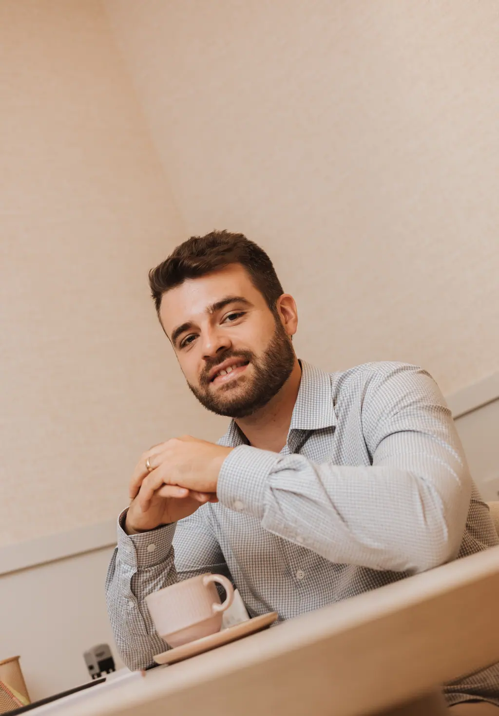 Dr. Lucas Vitório à mesa do consultório, com uma xícara de café